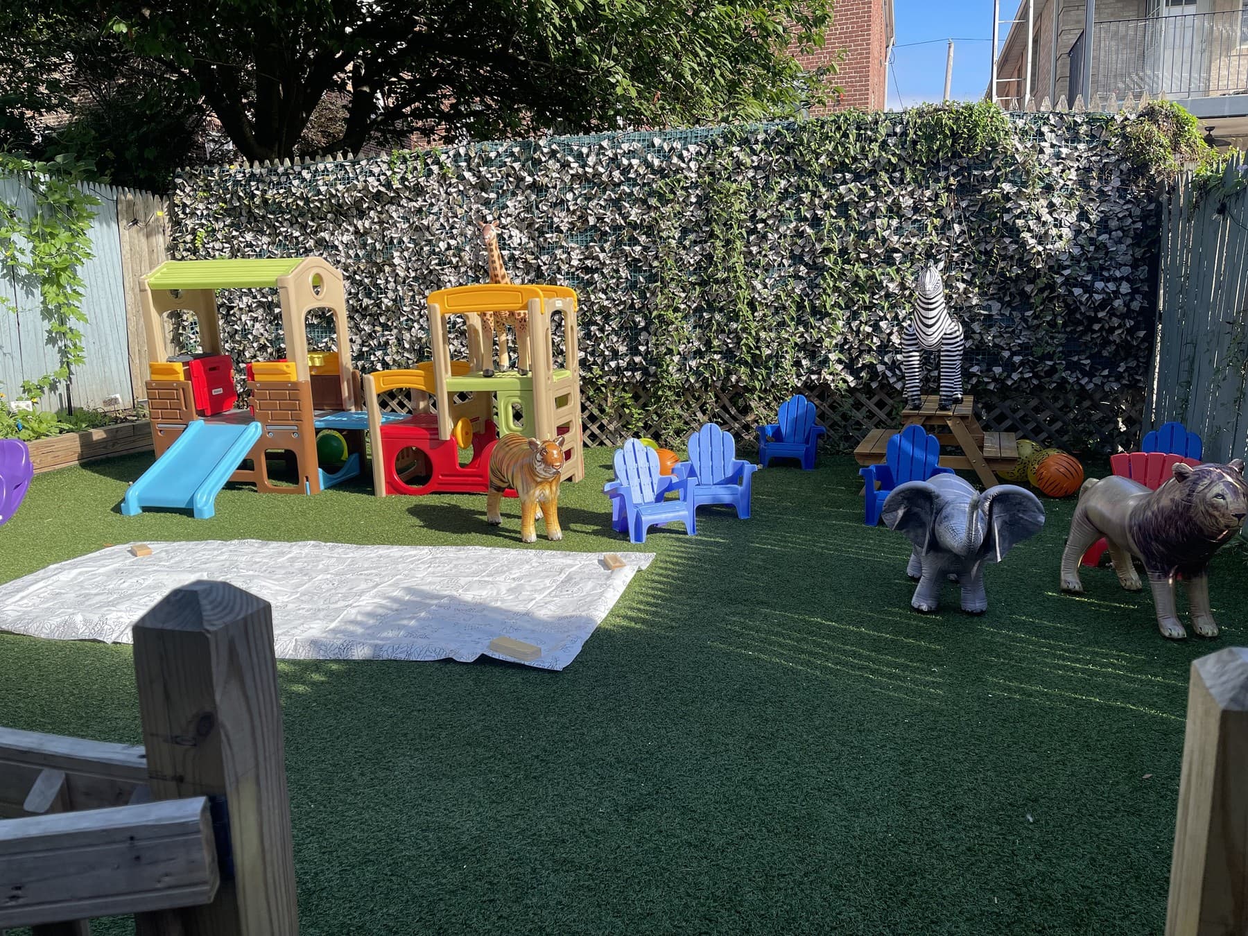 Private Woodlawn outdoor playground with green turf, a play structure, and space for children to explore