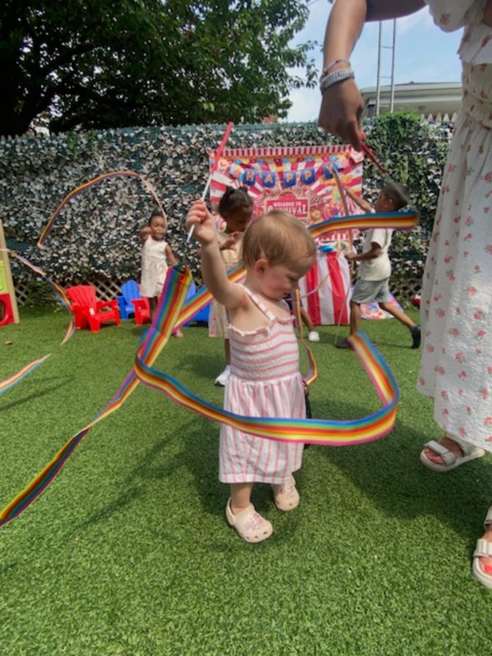 A child playing with colorful ribbons during an outdoor celebration