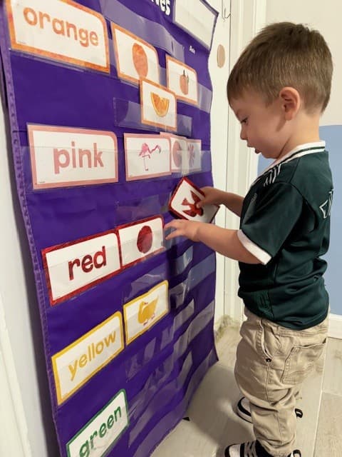 A child sorting color cards into a pocket chart during a colors activity