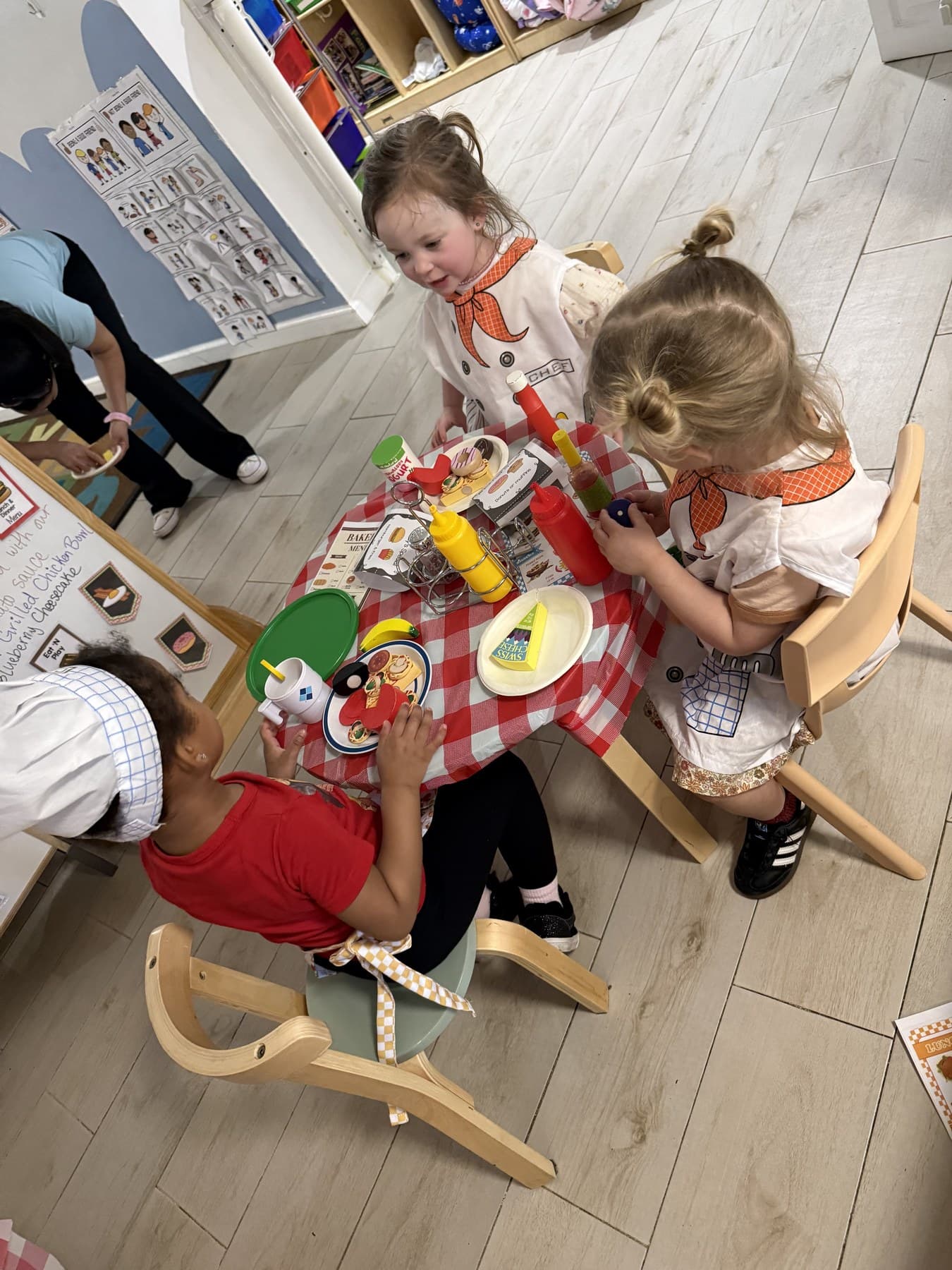 Babies sharing a pretend restaurant meal at a checkered tablecloth