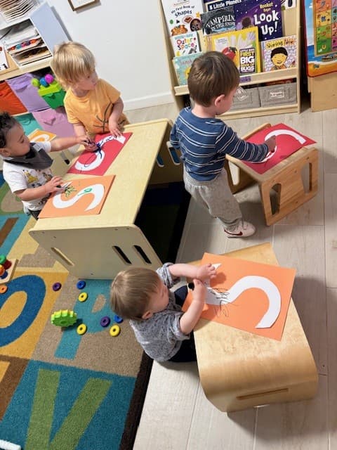 Young children coloring large letter S cutouts during an early literacy activity
