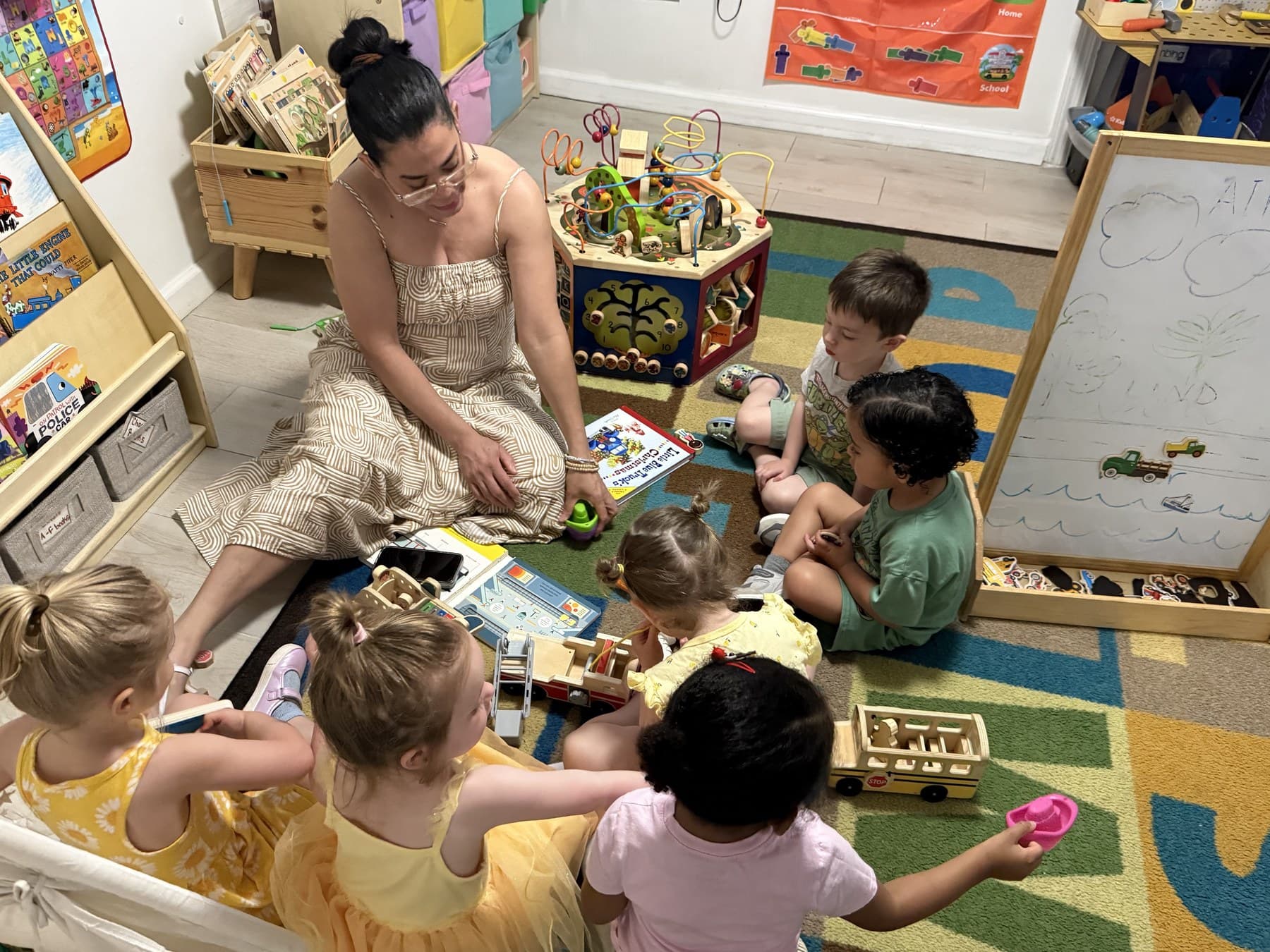 A Rising Scholars teacher and babies gathered on a classroom rug for playful learning with wooden toys