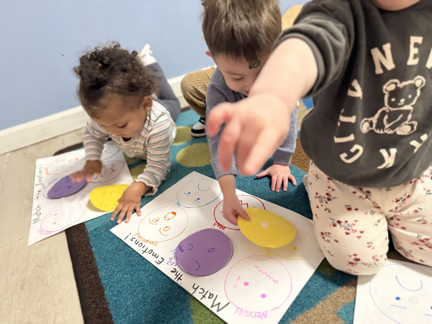 Babies matching emotion faces during a social-emotional learning activity on the classroom rug