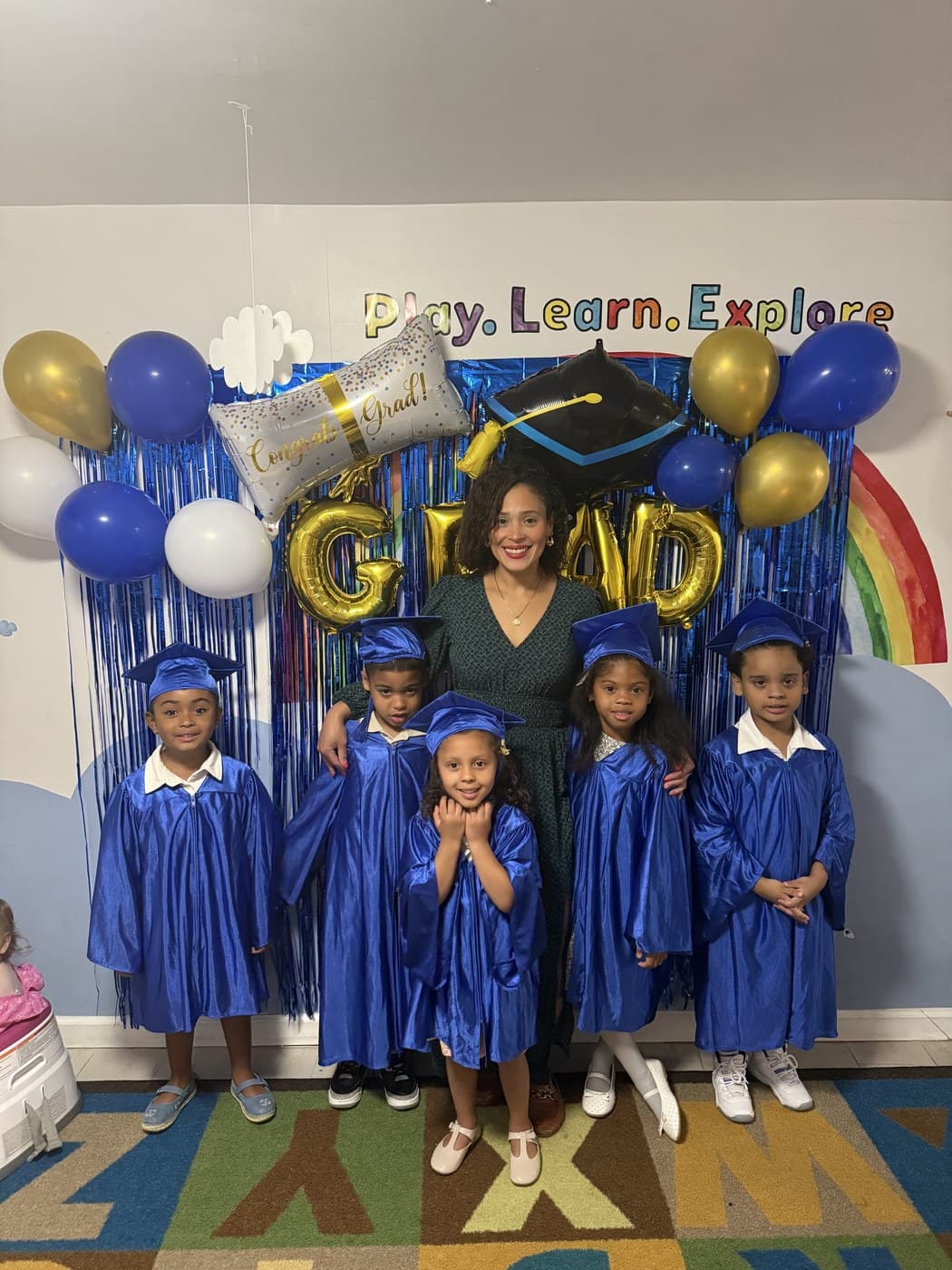 Rising Scholars toddlers in blue caps and gowns celebrating graduation with their teacher
