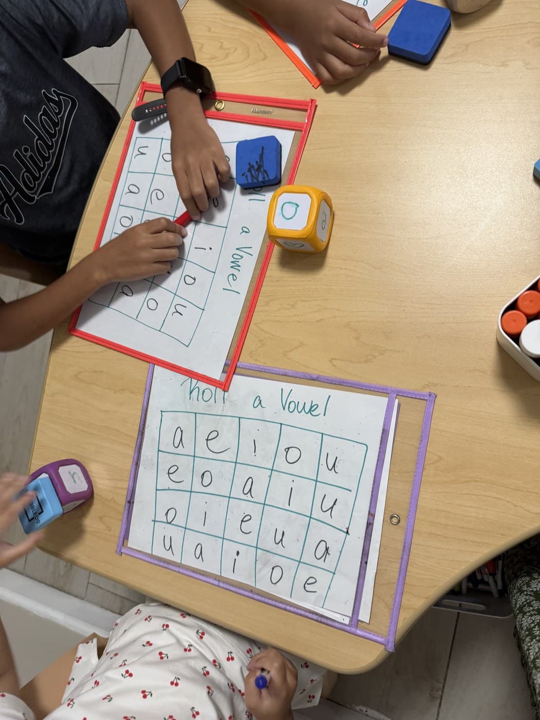 Toddlers practicing vowels with a Roll a Vowel activity and foam dice