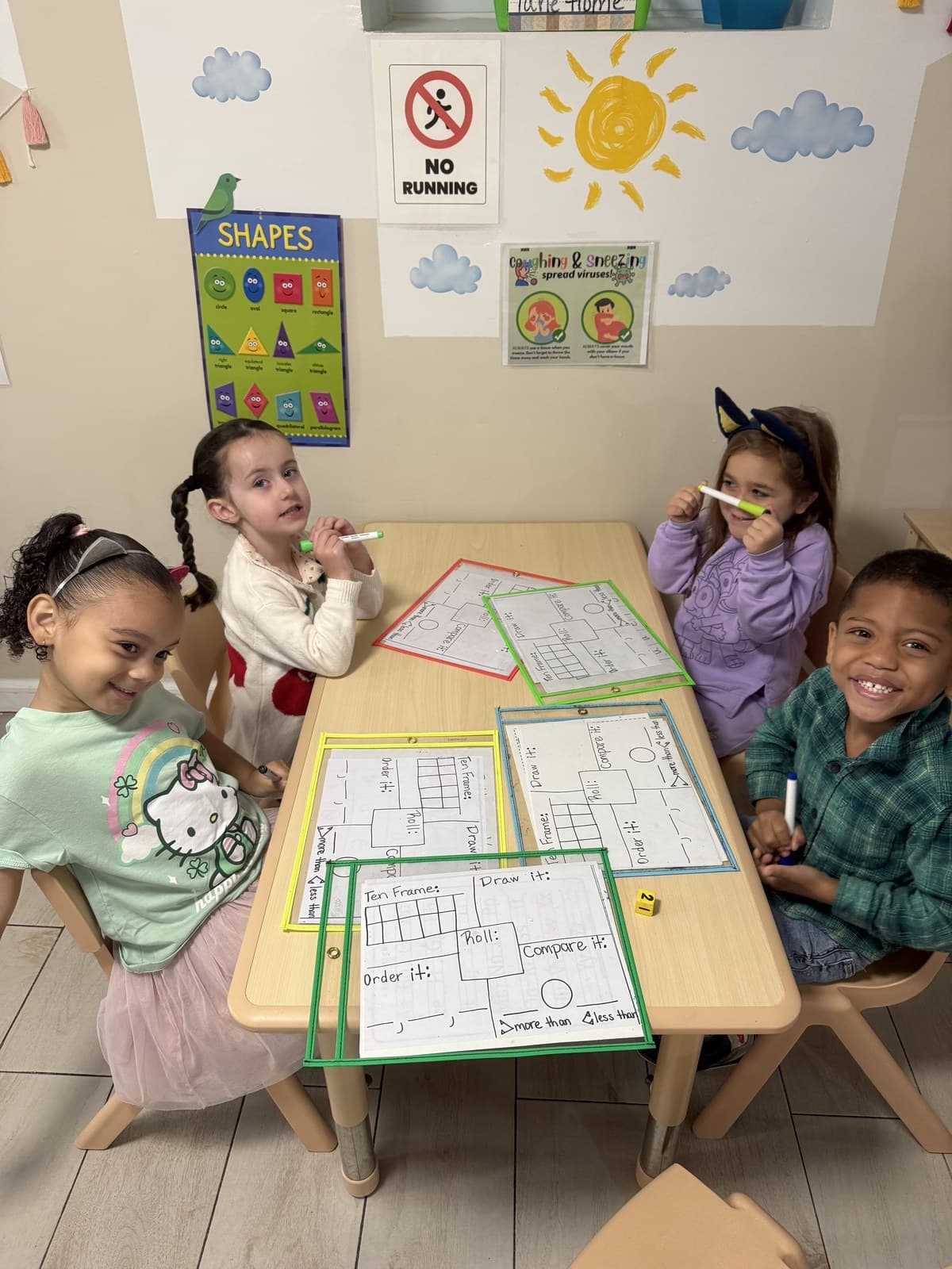 Toddlers working together at a table with ten frames, dice, and early number activities