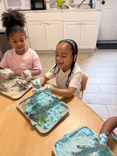 Toddlers exploring a hands-on sensory science activity with colorful foam at the table
